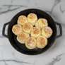 Baked biscuits in a cast iron skillet on a metal surface