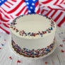 White cake with red and blue sprinkles on a marble surface