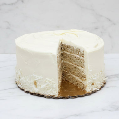White cake with a slice removed on a marble surface