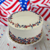 White cake with red and blue sprinkles on a marble surface